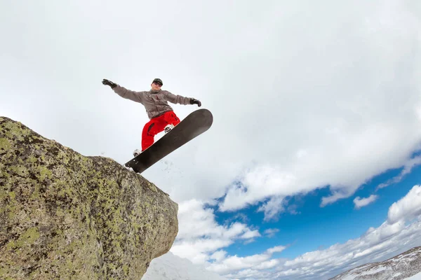Snowboarder springt uit grote rots — Stockfoto
