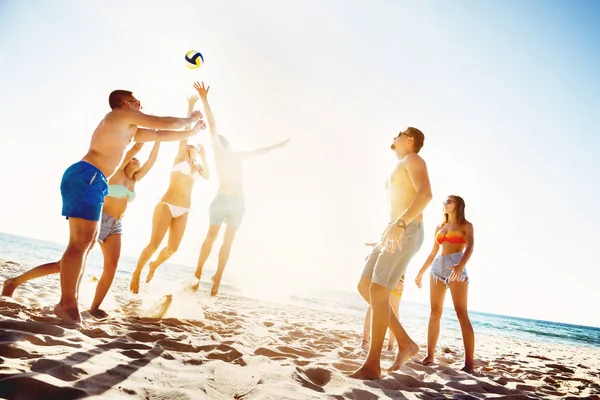 Amis jouant beach voleyball coucher de soleil — Photo