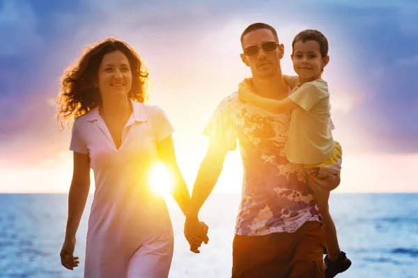 Família feliz andando na praia do por do sol — Fotografia de Stock