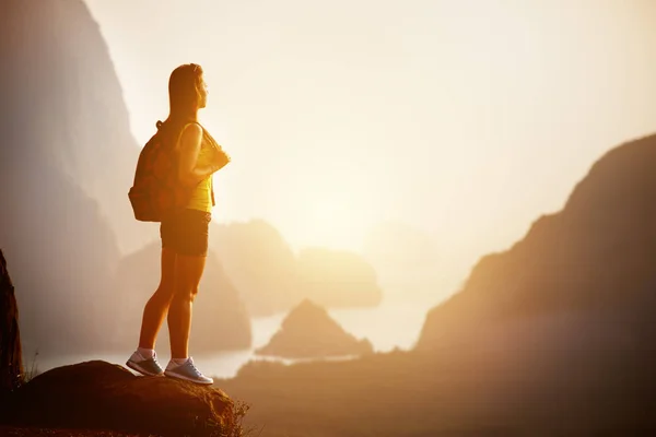 Mooie vrouw met rugzak bij zonsopgang of zonsondergang op de bergtop — Stockfoto