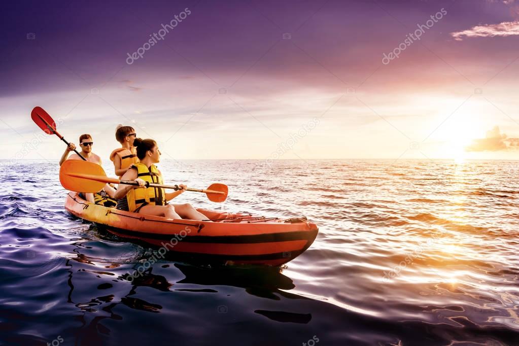 Happy family swims kayaking at sea sunset