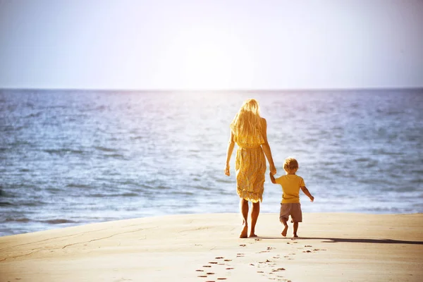 Mère et jeune fils marchent plage — Photo