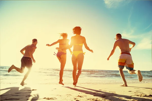 Щасливі друзі проводять захід сонця пляжний відпочинок — стокове фото