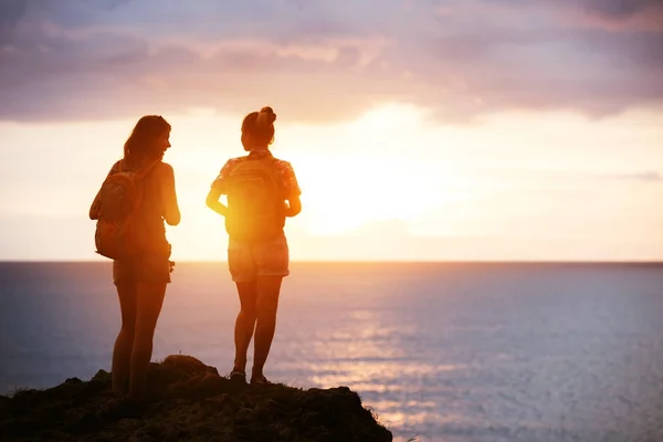 Две девушки путешествуют на морском закате — стоковое фото
