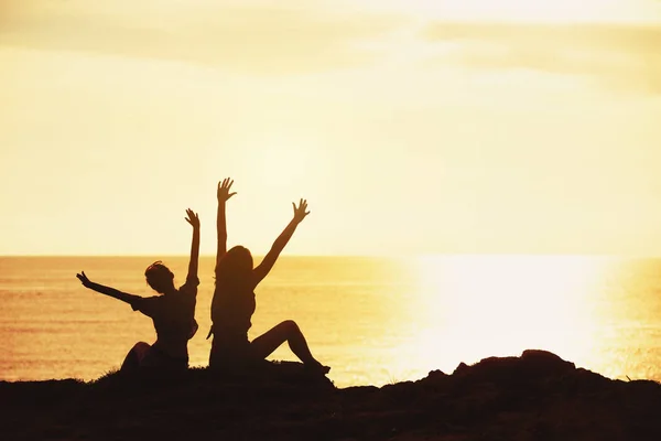 Δύο κορίτσια ευτυχισμένη χαιρετισμό ηλιοβασίλεμα στη θάλασσα — Φωτογραφία Αρχείου