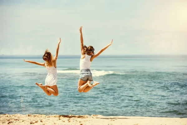 Zwei glückliche Mädchen springen am sonnigen Strand — Stockfoto