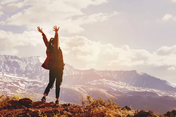 Lycklig kvinna med upphöjda händer på bakgrund av bergen sunset — Stockfoto