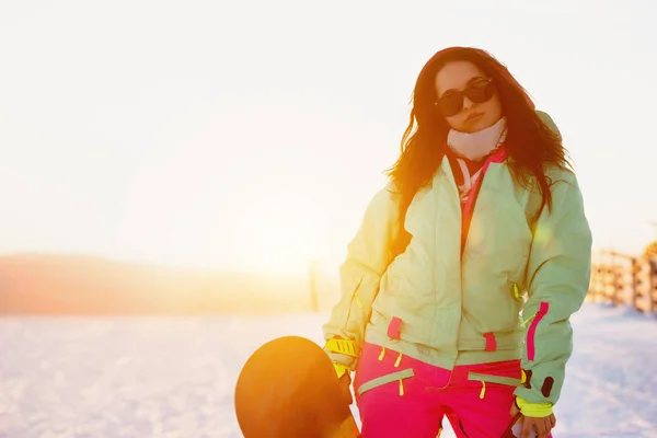 Красива леді зі сноубордом на лижному схилі заходу сонця — стокове фото