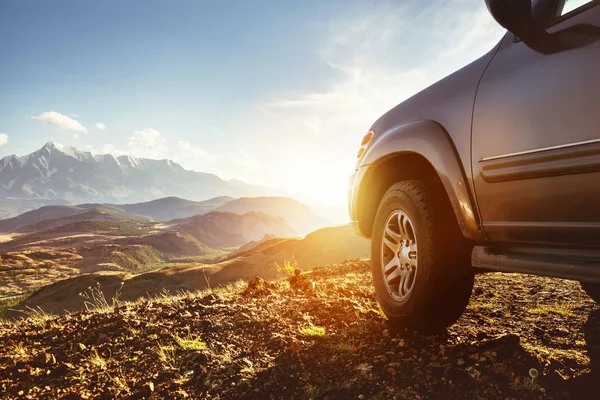 Grande carro 4x4 contra o pôr do sol e montanhas — Fotografia de Stock