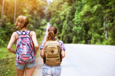İki kız sırt çantaları ile düz yoldan gidiyoruz