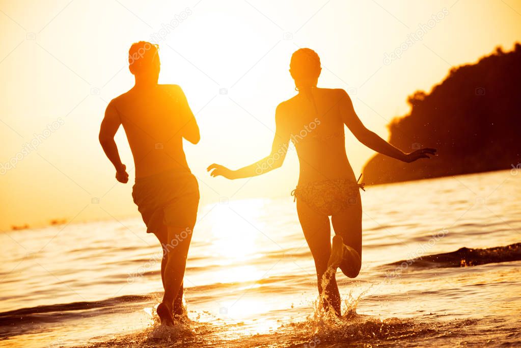 Happy couple run to sunset sea