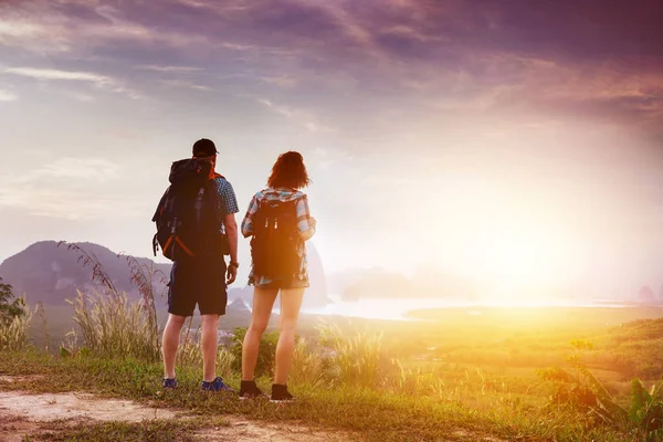 Paar backpackers kijken bij zonsopgang of zonsondergang in de buurt van de zee baai en eilanden — Stockfoto