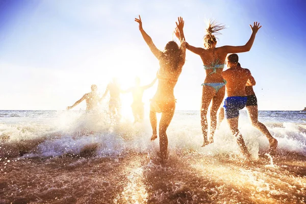 Happy přátelé v západu slunce moře beach — Stock fotografie