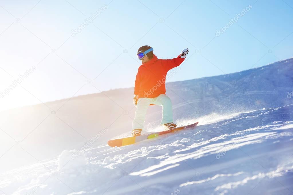 Lady snowboarder at ski slope in sun light