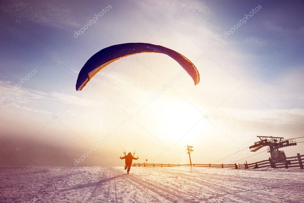 Skydiver runs or starts flight at sunset mountain