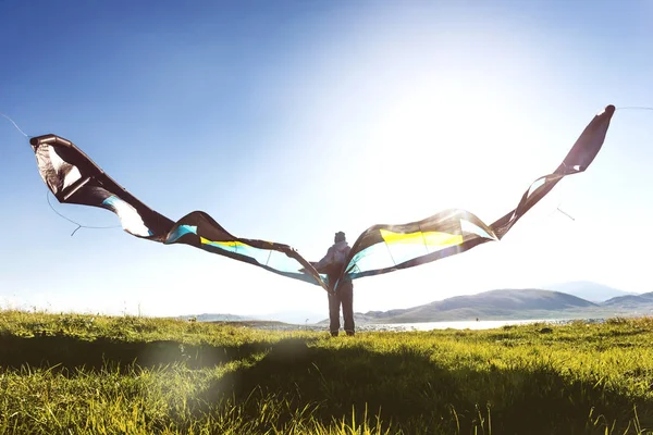 Man woman stands with kite in sun light