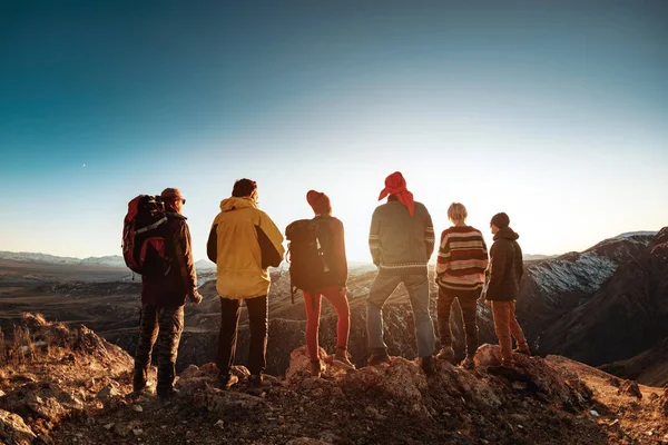 Groep zes toeristen tegen zonsondergang licht en bergen — Stockfoto