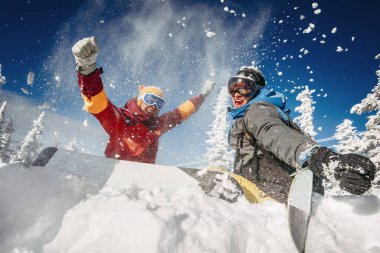 Mutlu çift snowboardcular ormanda eğleniyor.