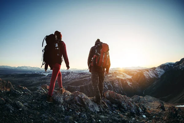 Két túrázó sétál a naplemente hegyekben. — Stock Fotó