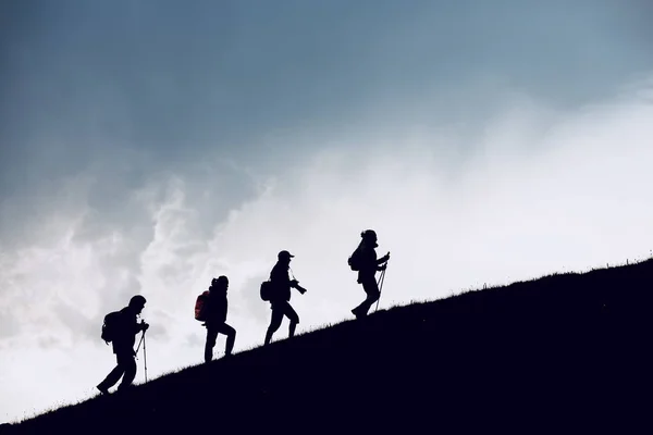 Cuatro siluetas de excursionistas va cuesta arriba — Foto de Stock