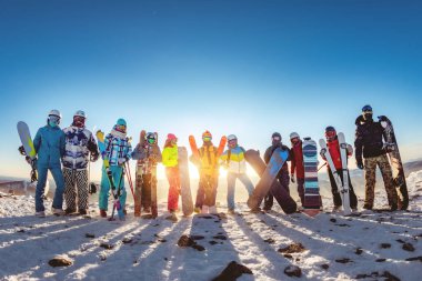 Gün batımında büyük bir kayakçı ve snowboardcu grubu.