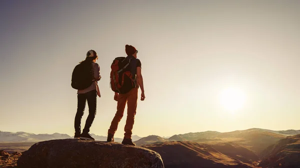 Dwóch podróżników stoi przy zachodzie słońca w górach. — Zdjęcie stockowe