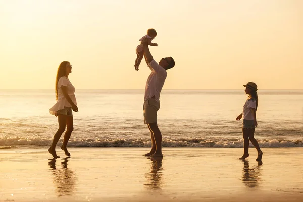Семья с двумя дочерьми играют на морском пляже — стоковое фото