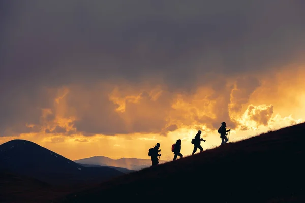 一群徒步旅行者在雄伟的落日下漫步在群山中 — 图库照片