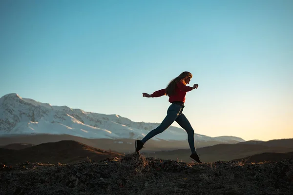 Smal sportig flicka promenader vid solnedgången i bergen — Stockfoto