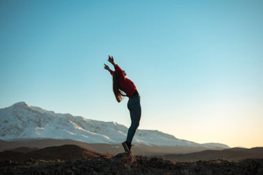 Young active girl in winner pose in mountains clipart