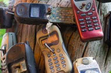Ağaca çivilenmiş kırık eski cep telefonları