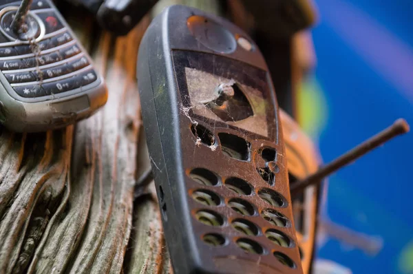 Ağaca çivilenmiş kırık eski cep telefonları — Stok fotoğraf