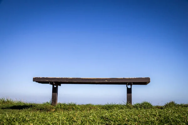 Bank op groene gras met bankje wit helderblauwe hemelachtergrond — Stockfoto