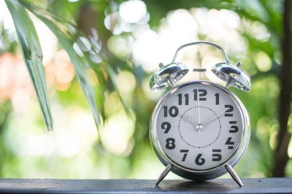 庭の背景を持つ古典的な目覚まし時計. — ストック写真