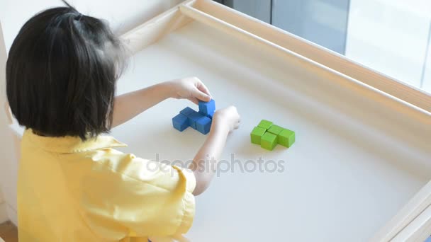 Dívka hraje dřevěná krabice na stole. — Stock video