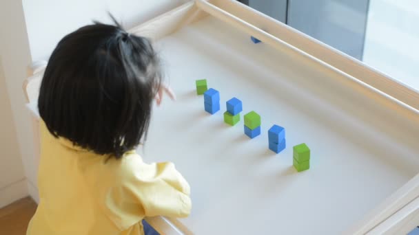 A girl playing wooden box on table. — Stock Video