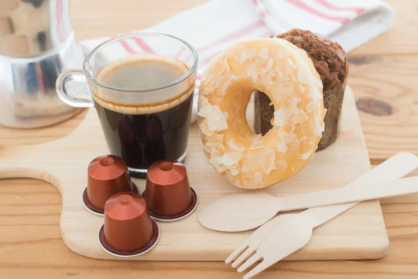 Xícara de café expresso e cápsula de café expresso com padaria em mesa de madeira . — Fotografia de Stock