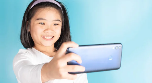 Asian children are holding mobile phones by searching for knowledge from online media there are many on the internet to improve knowledge. Ability in various fields Including for fun and entertainment In today\'s world.