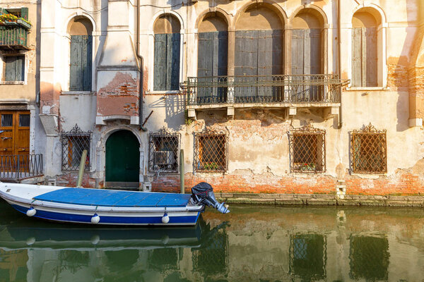 Small canal in Venice with old buildings balconies