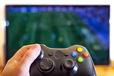 T üzerinde spor oyunu oynarken el holding oyun konsolu denetleyicisi