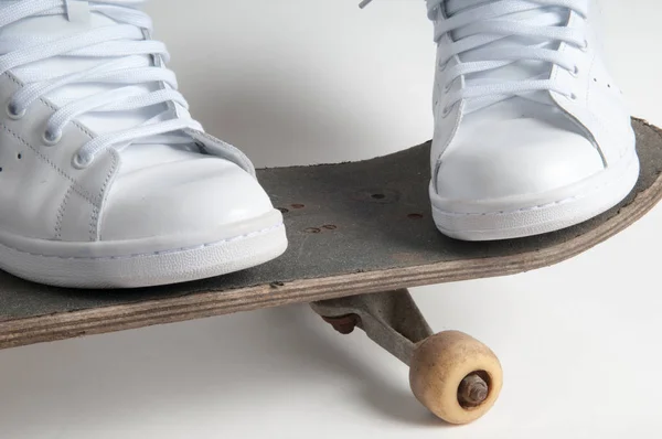skateboarding person stands with feet apart on an old skateboard