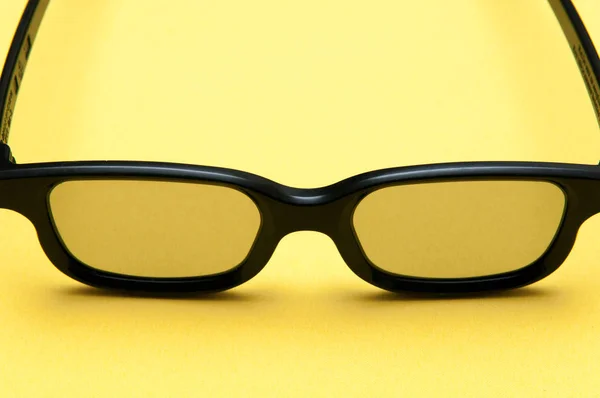 Óculos com moldura preta sobre fundo amarelo — Fotografia de Stock