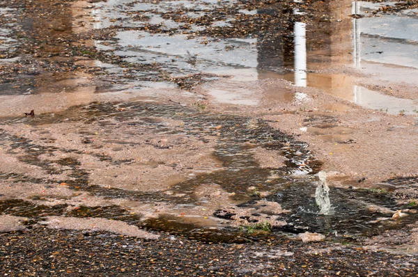 water damage to road from burst leaking water pipe