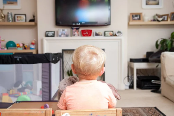 Małe dziecko w domu oglądając televsion siedzi na krześle małe — Zdjęcie stockowe