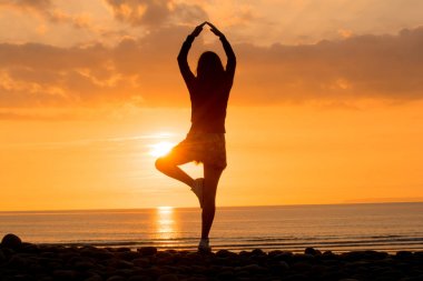 Yoga gün batımında sahilde pratik kadın