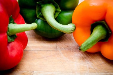 doğrama tahtası üzerinde kırmızı yeşil ve sarı biber