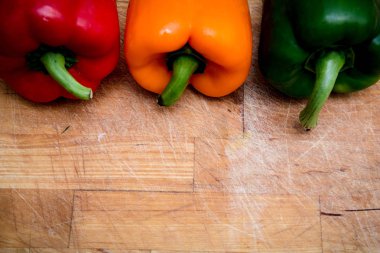 doğrama tahtası üzerinde kırmızı yeşil ve sarı biber