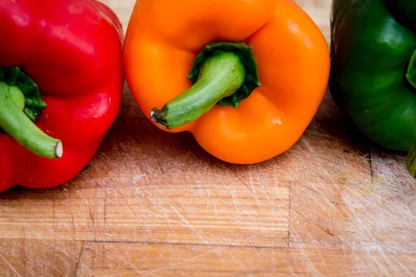 doğrama tahtası üzerinde kırmızı yeşil ve sarı biber