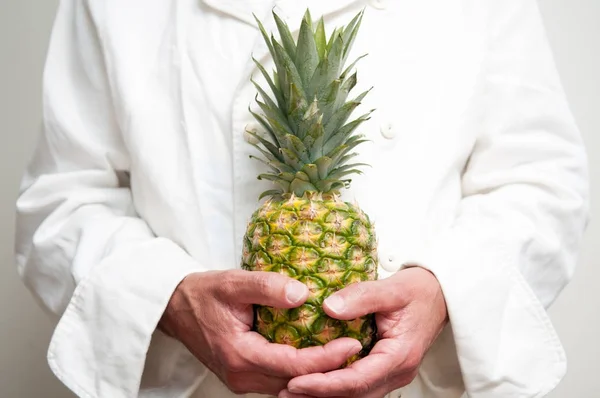 Un hombre tiene fruta, una piña fresca — Foto de Stock