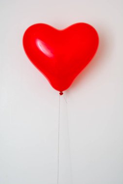 Kırmızı kalp şeklinde balon üzerinde beyaz izole bir ipte